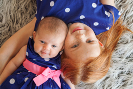 newborn girl with older sister in matching dresses photographed from above