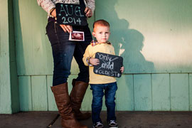 expectant mom with a sign saying their due date, toddler holding a sign that say oldest
