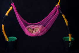 Newborn baby girl in pink hammock