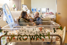 family in hospital recovery room with newborn baby sleeping