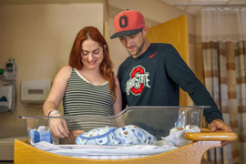 family in hospital recovery room with newborn baby sleeping